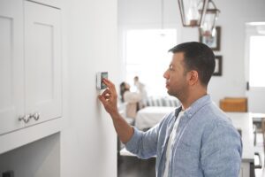 man adjusting thermostat in the kitchen